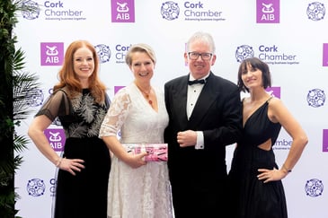 Three white women and one white man dressed up at a black-tie ball