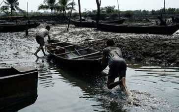 Two men pushing a wooden boat ashore