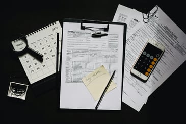 A clip board, calculator and papers on a table